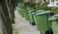 residential street lined with green wheelie bins