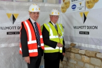 men standing by half-built wall for new cemetery ceremony