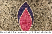 artwork made with hand prints. A red and purple flame against a yellow/grey background. Captions says 'handprint flame made by Solihull students'
