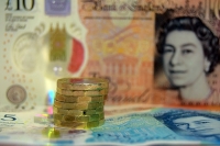 Pound coins stacked on top of notes