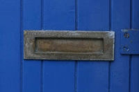 Closeup of an iron letterbox in a blue painted wooden door