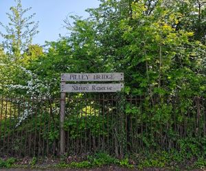 Wooden sign in front of lush green vegetation says "Pilley Bridge Nature Reserve"
