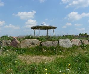 Metal shelter shaped like a UFO in Springfields Park, surrounded by large rocks and natural planting