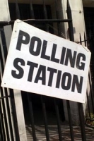 Polling station sign, large black lettering on white background secured to iron railings