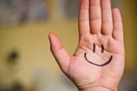 Hand held up, palm facing forward with a smiley face drawn on it