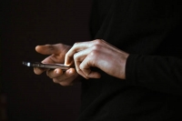 Hands holding a mobile phone surrounded in darkness