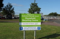 Sign on a grass verge in front of the Swindon Road recycling centre reads 'Household recycling centre' in white letters on a green background