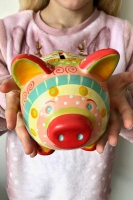 Girl in a pink top holds a colourful patterned piggy bank