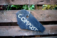 wooden compost bin with the word compost painted onto a slate sign