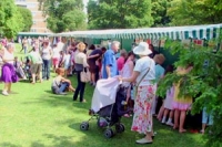 Woman in summer hat with pushchair amongst other visitors to the fiesta stalls